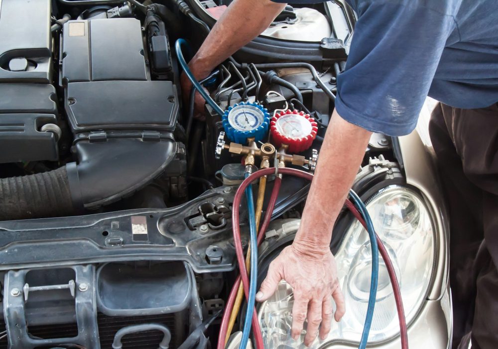 Mechanic with manometer inspecting auto vehicle air-condition co